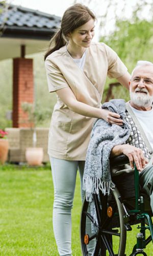 Senior man with helpful volunteer in the garden of professional care home